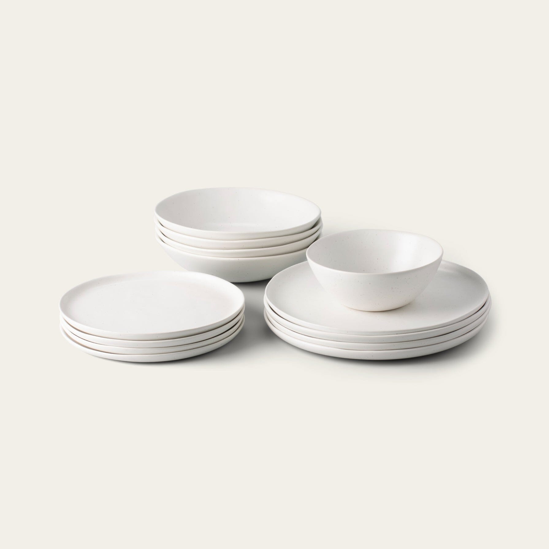 Stacked white bowls and plates on a plain background.
