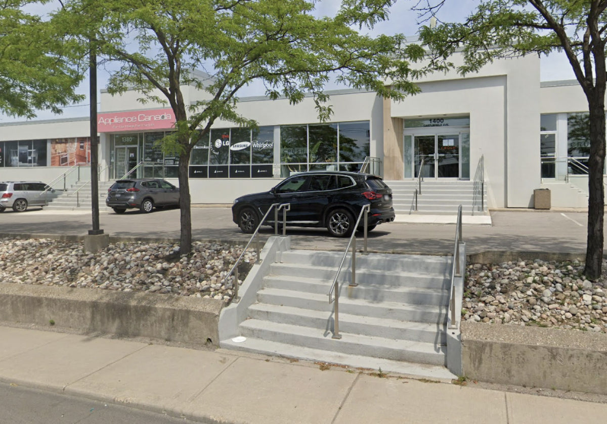 Exterior street view of the Toronto warehouse sale venue with a parked SUV and concrete entrance steps