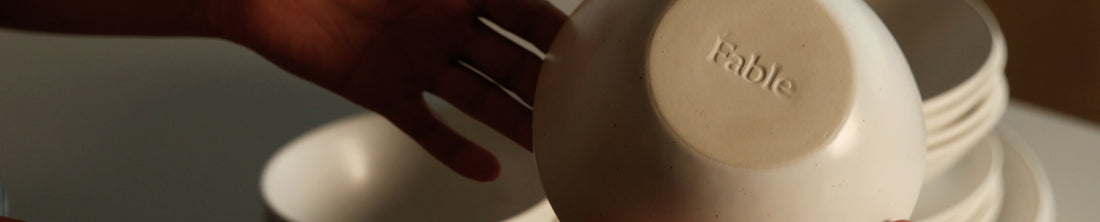 Hand lifting white bowl to reveal Fable stamp on the underside