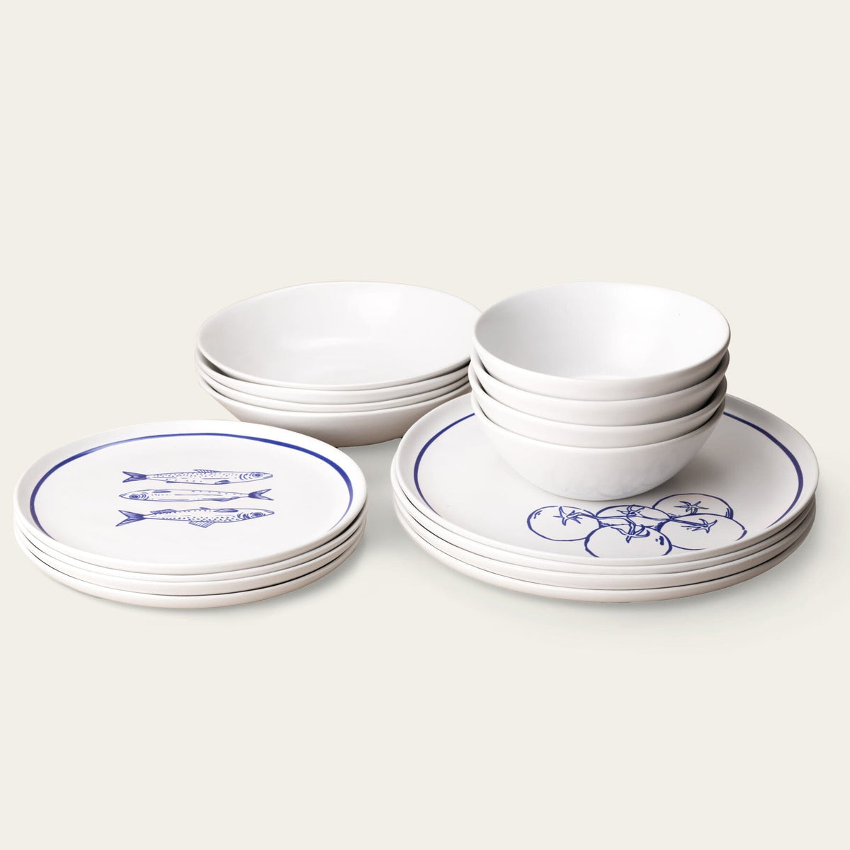 Set of white ceramic plates and bowls with blue designs on a light gray background