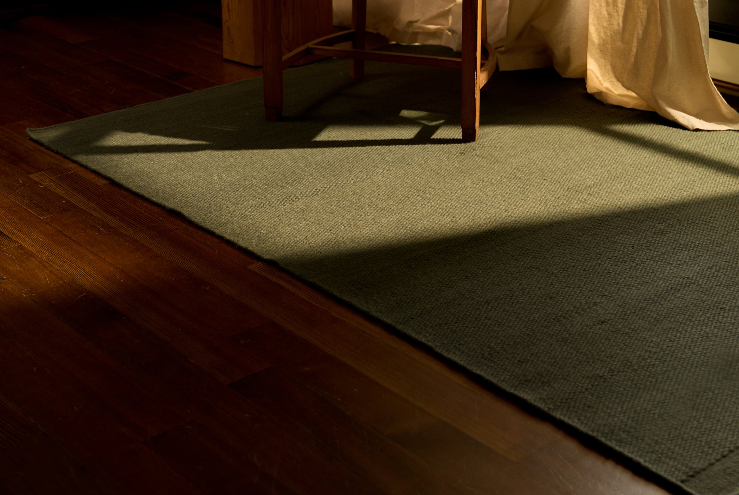 Green rug on a wooden floor with a chair partially visible