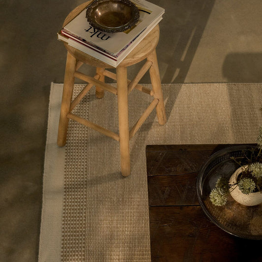 Wooden stool with a book on top, placed on a textured rug. #coastalcream