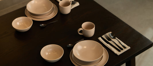 Fable beige matte stoneware dinnerware with black flatware on a dark wood dining table