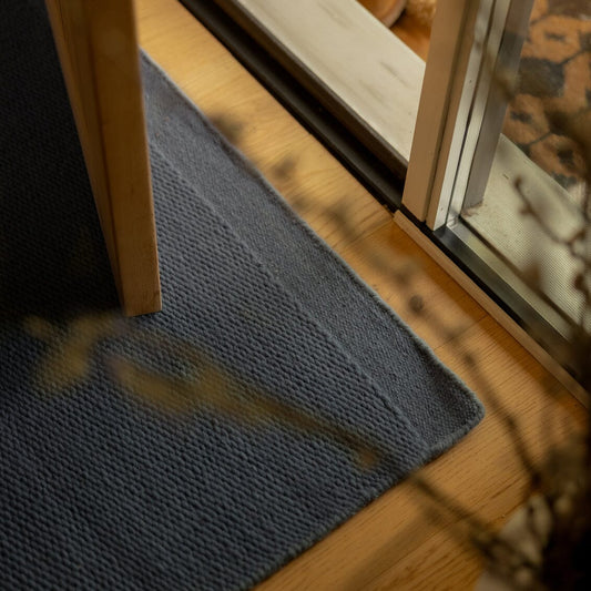 Blue rug on a wooden floor next to a glass door. #seasideblue